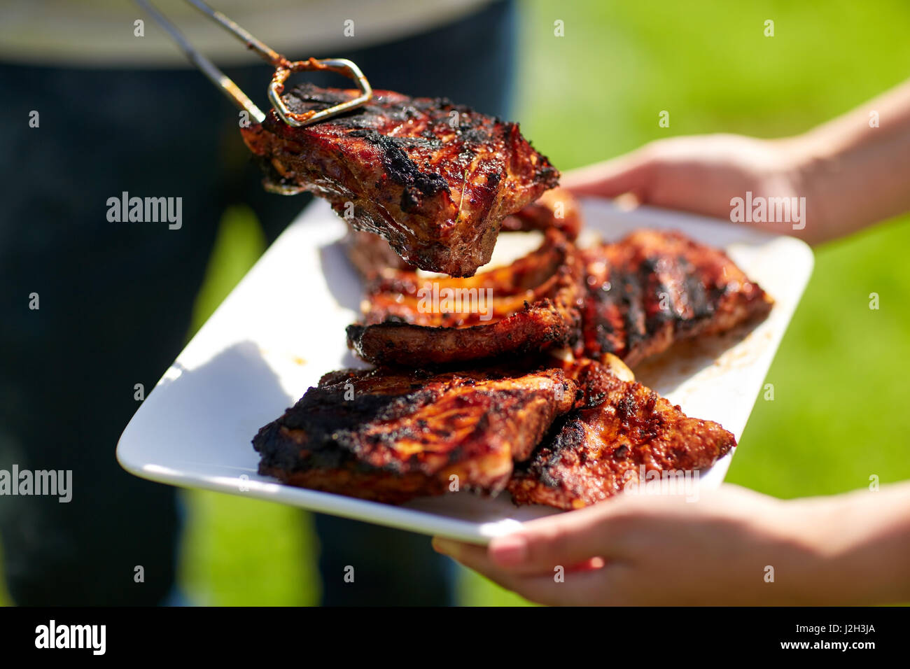 L'uomo la cottura della carne in estate barbecue party Foto Stock