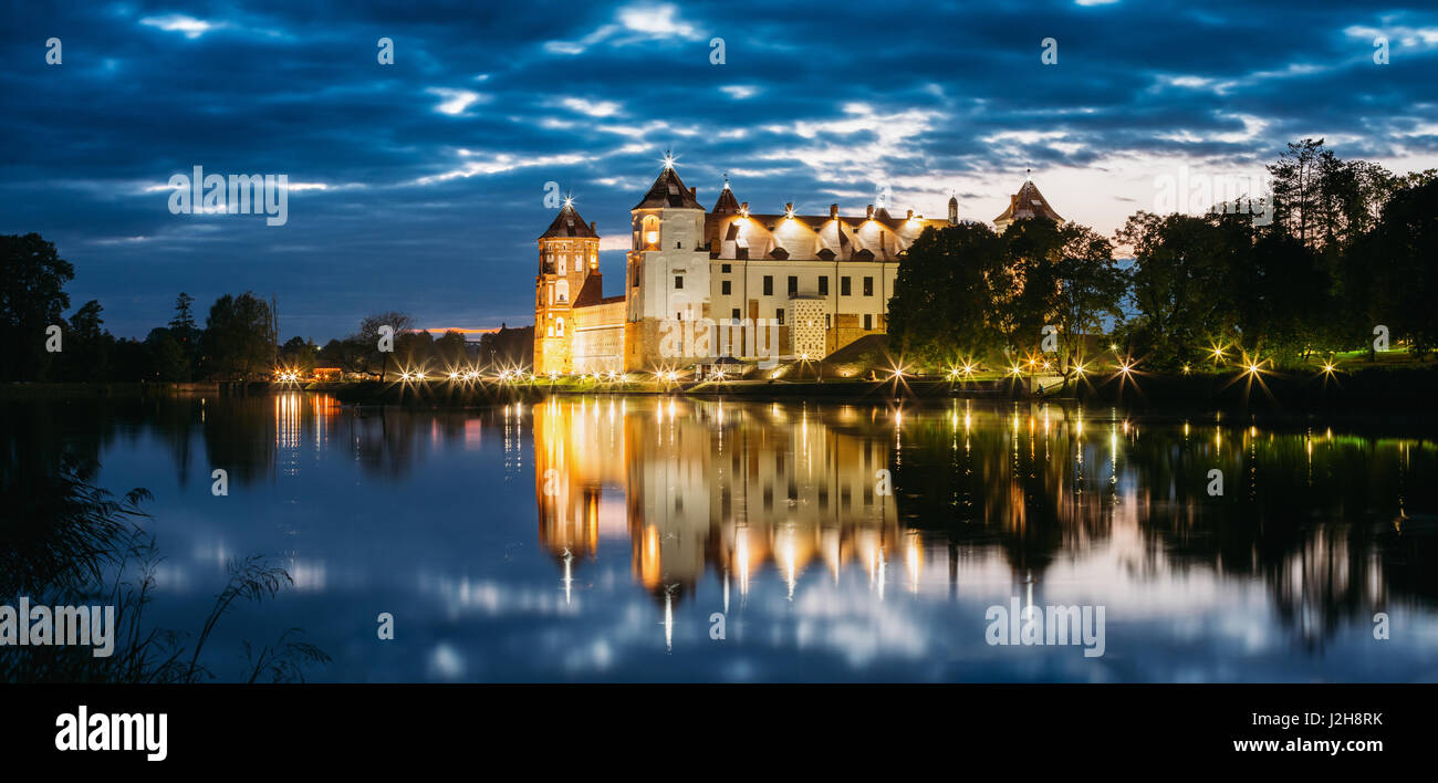 Mir, Bielorussia. Panorama del complesso del Castello di Mir In brillante illuminazione serale con candelette di riflessioni sul lago di acqua. Famoso punto di riferimento, antichi Monum gotica Foto Stock