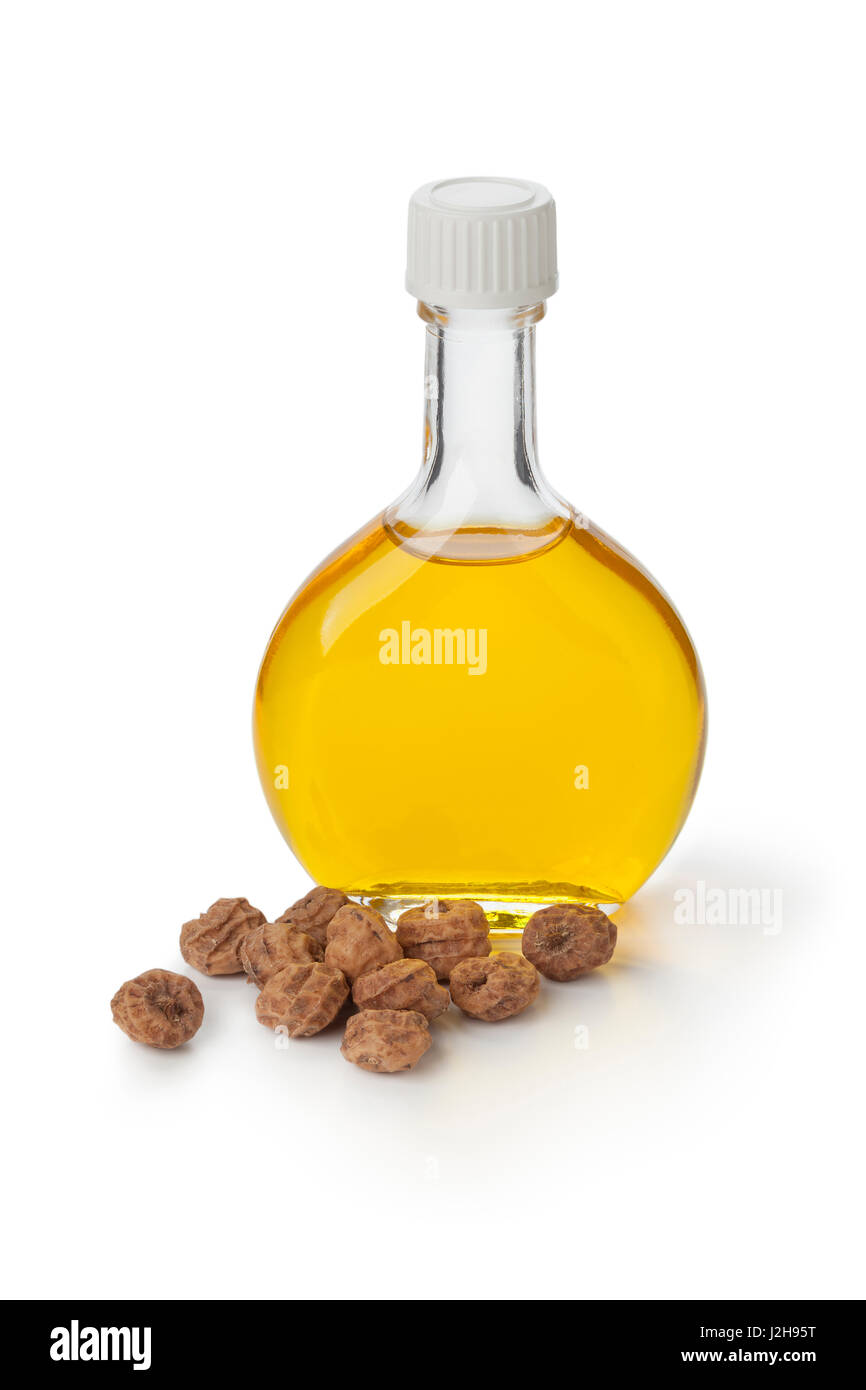 Bottiglia di vetro con "Chufa olio e i dadi su sfondo bianco Foto Stock