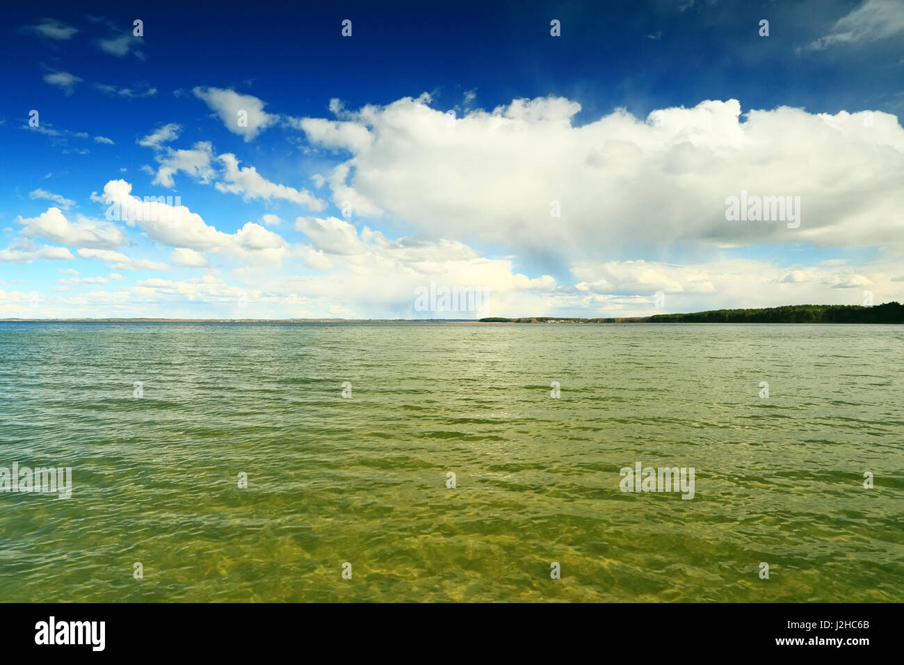 Il cielo blu con nuvole bianche su chiare acque trasparenti. Giornata di sole sul lago. Foto Stock