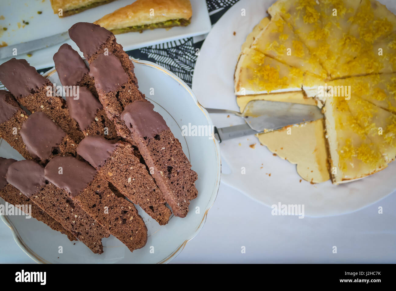 Tabella di dessert con biscotti al cioccolato e cheesecake su bianco che serve piatti Foto Stock