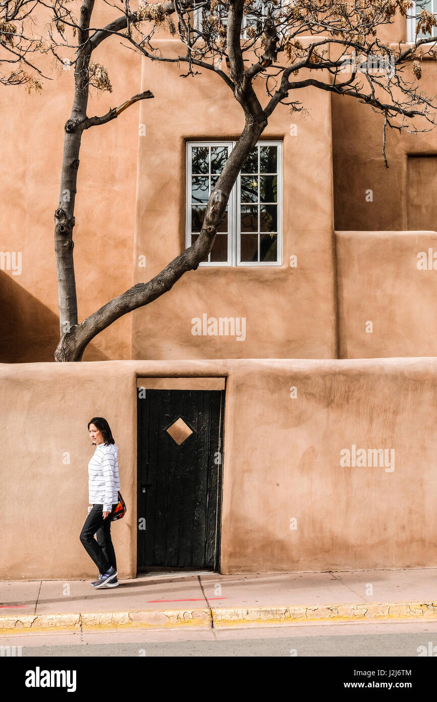 Una donna a piedi nella parte anteriore del adobe edificio di stile a Santa Fe, New Mexico Foto Stock