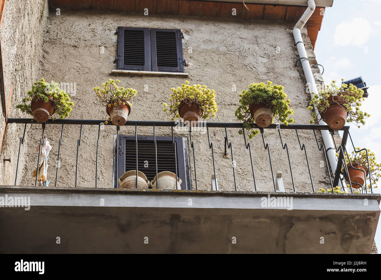 La facciata della casa e balcone con vasi da fiori in un piccolo villaggio nel centro dell'Italia. Foto Stock