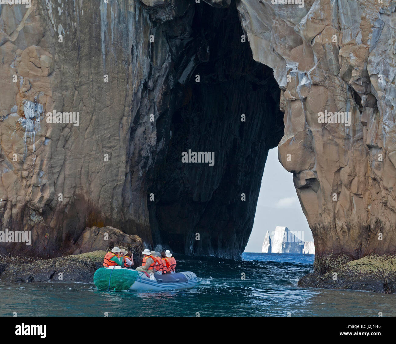I turisti delle Galapagos a bordo di una barca panga ammirano Kicker Rock attraverso un passaggio di pietra, l'isola di San Cristobal Foto Stock