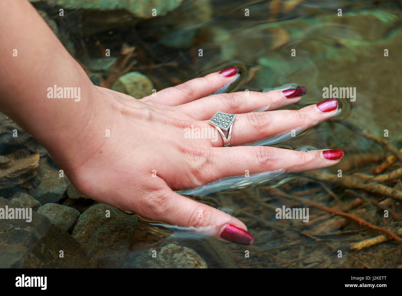 Donna di mano acqua toccante Foto Stock