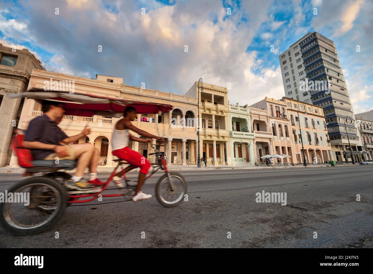 L'Avana - Giugno, 2011: un cubano taxi bicicletta pedali il suo modo di fronte all'architettura di sbriciolamento di Malecon strada lungomare. Foto Stock