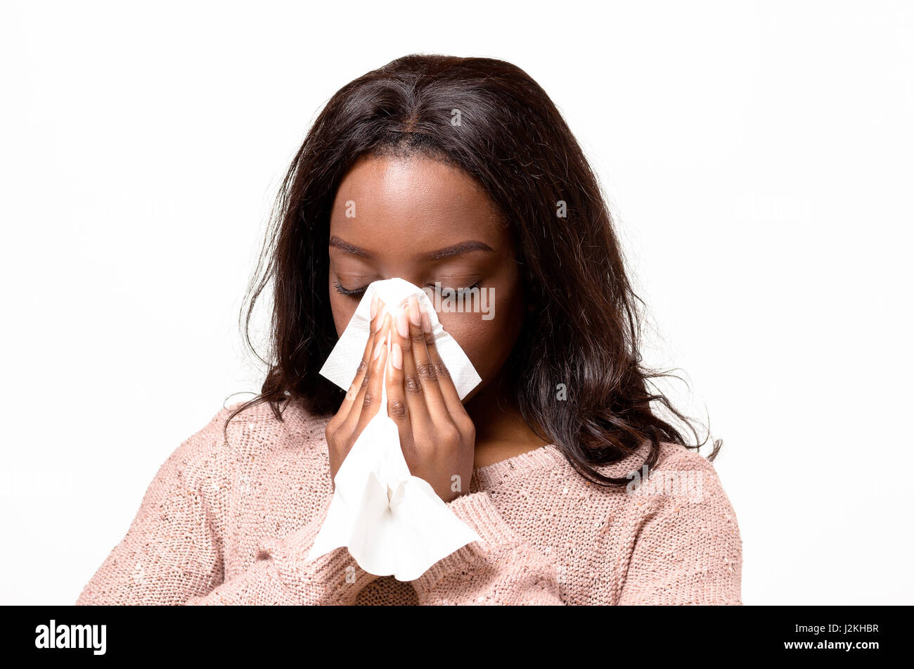 Uno stato di malessere, giovane donna soffia il naso su un tessuto bianco concettuale del l'influenza stagionale e raffreddori, allergia, rinite o hayfever, testa e spalle su bianco Foto Stock
