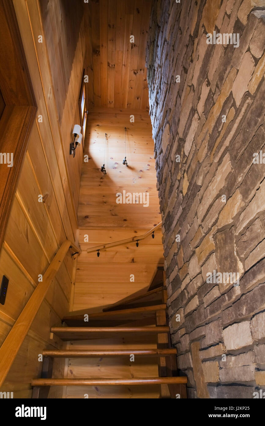 Scala di legno fiancheggiato da tavola orizzontale e i muri in pietra  naturale che conduce al piano superiore all'interno di piani in stile  cottage piatto profilo di registro e legname home Foto