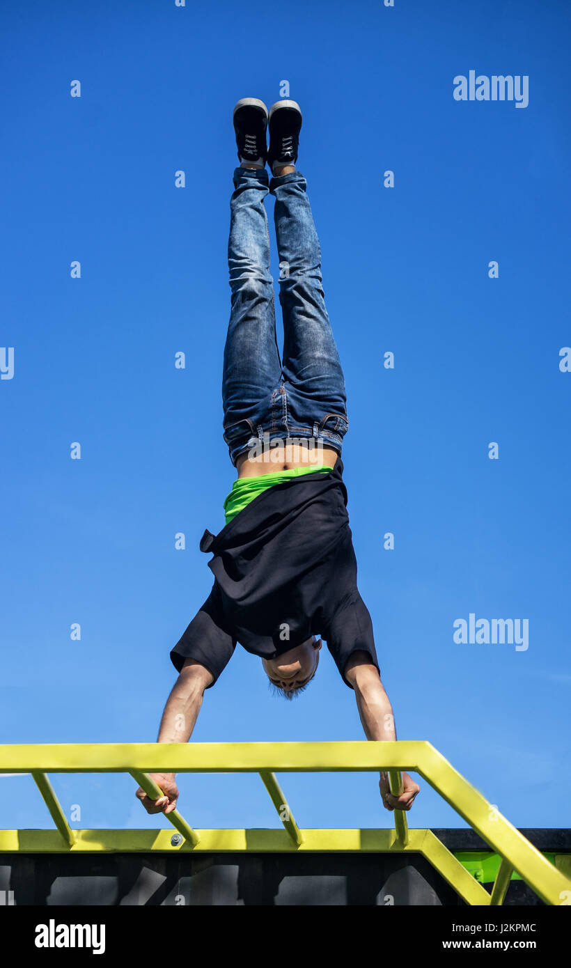Giovane atleta facendo una mano Stand su barre parallele in una palestra a cielo aperto Foto Stock