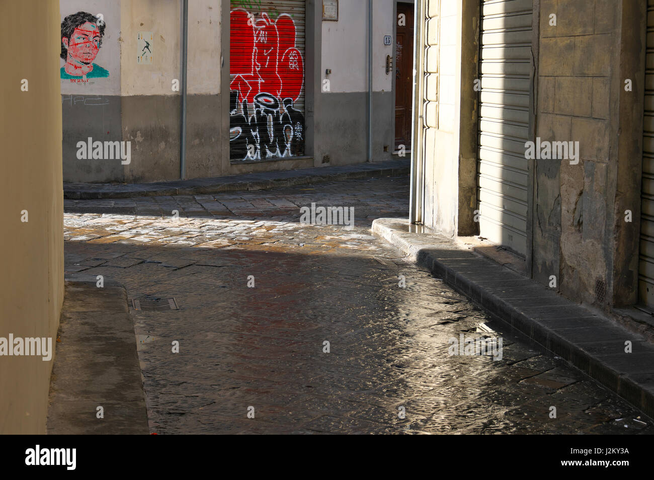 Il sole splende dopo la pioggia, pavimento bagnato in un vicolo di Firenze, Firenze, Toscana, Italia, Europa - colorata graffiti sulle pareti e otturatore Foto Stock
