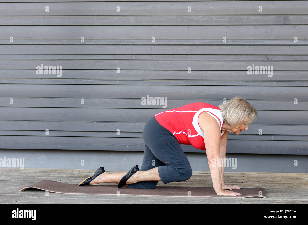 Senior donna facendo esercizi di fitness su un tappetino palestra sollevando i suoi piedi in aria per rafforzare i suoi muscoli addominali Foto Stock