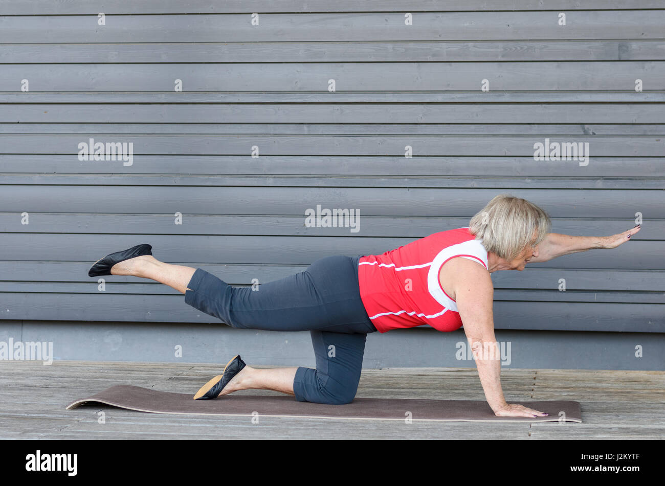 Senior donna facendo esercizi di fitness su un tappetino palestra sollevando i suoi piedi in aria per rafforzare i suoi muscoli addominali Foto Stock
