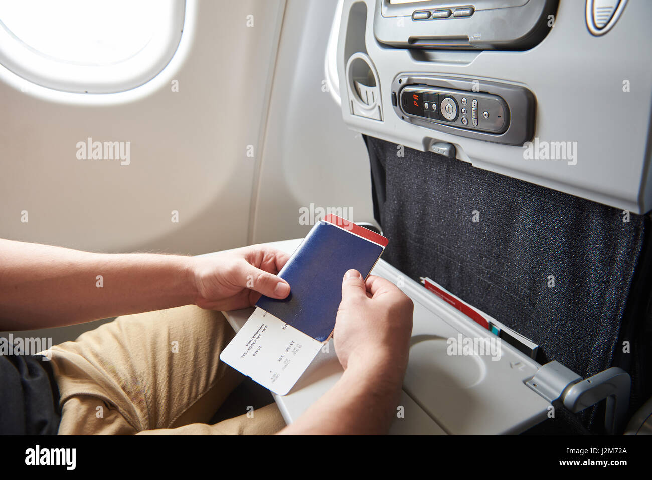 Uomo in aereo con il passaporto in mano in attesa del volo successivo Foto Stock