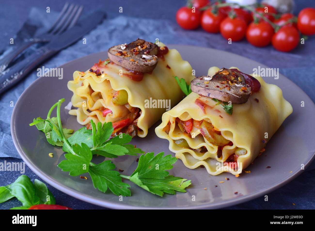Pronto a mangiare Lasagne Vegetariane in rotoli con funghi, paprica, olive, la salsa di pomodoro su un marrone piastra ceramica. Cibo sano. Cibo vegetariano. Passo dopo passo la cottura. Foto Stock