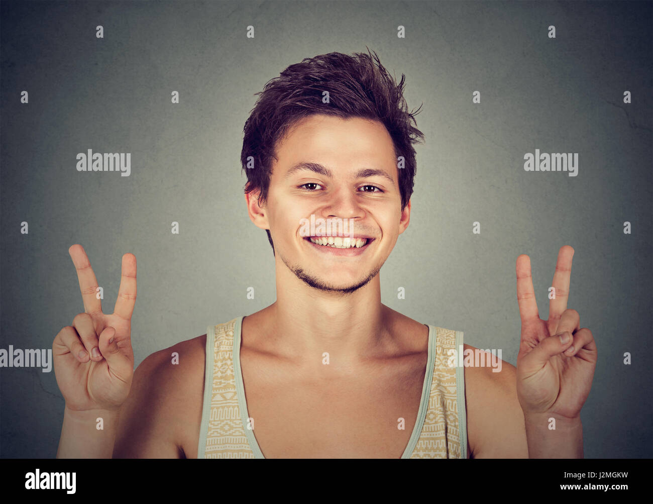 Il giovane studente bello tenendo in mano la pace vittoria, due isolati di segno uno sfondo grigio. Positivo emozione umana espressione facciale di atteggiamento dei simboli. Li Foto Stock