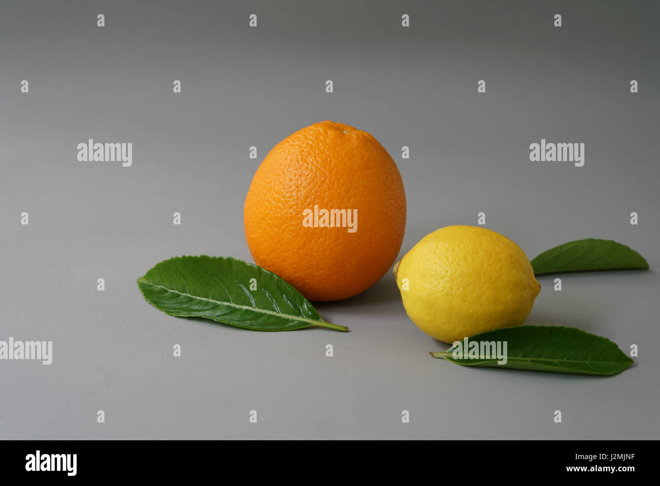 Organici di arancia e di limone su sfondo grigio - isolato Foto Stock