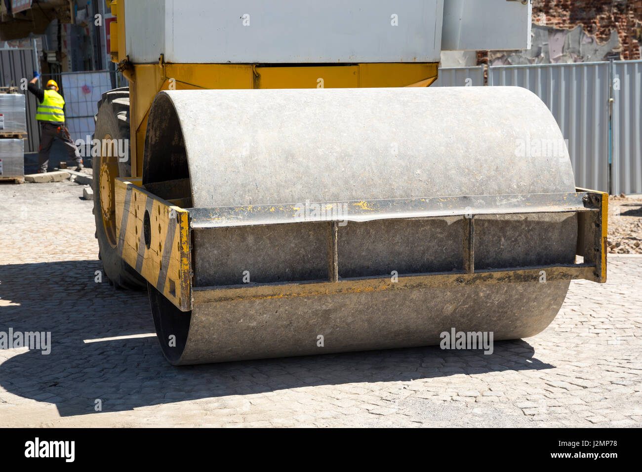 Dividere il tamburo del rullo vibrante in un cantiere smussa la pavimentazione sulla terra. Giornata di sole. Foto Stock