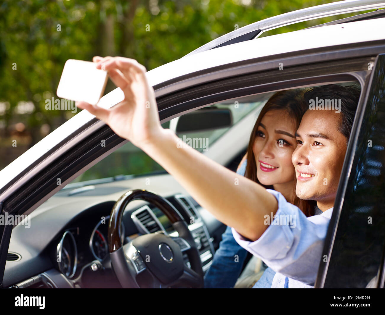 Asian giovane prendendo un selfie durante i viaggi in automobile. Foto Stock