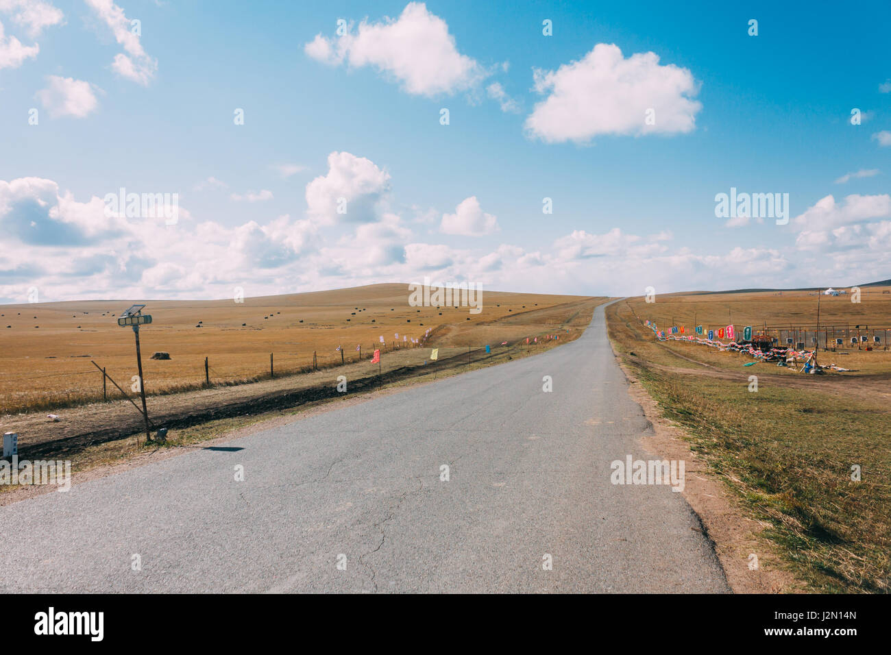 Terreni agricoli vuota strada nella prateria, cielo blu e nuvole bianche. Mattina. Mongolia interna, Foto Stock