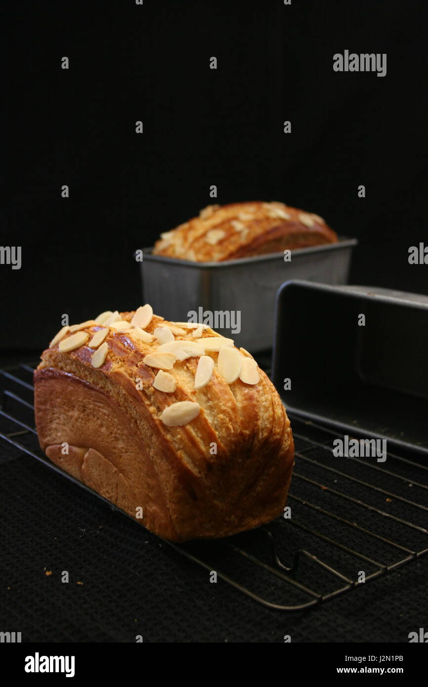 Toast di noce di cocco con scaglie di mandorle Topping, torta di metallo Raffreddamento per rack, e stagno Toast stampo da forno Foto Stock