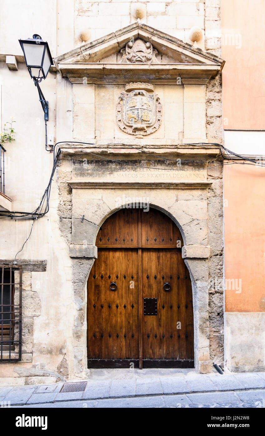 Legno vecchio porte doppie al di sotto di un frontone triangolare e stemma su un edificio storico nella città medievale di Cuenca, Spagna Foto Stock