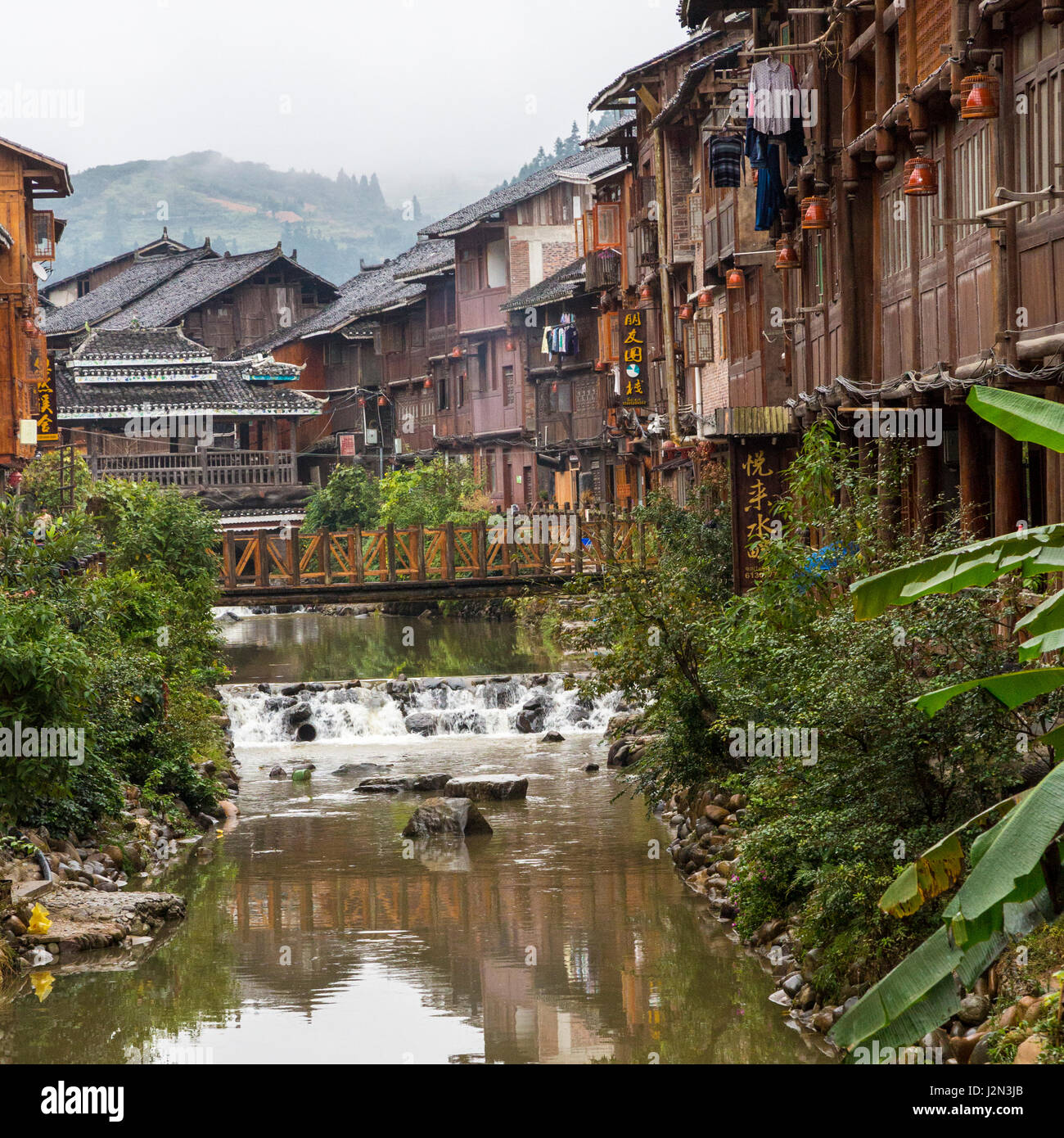 Zhaoxing, Guizhou, Cina, a Dong villaggio di minoranza. Negozi e case la linea i lati del piccolo fiume che attraversa il villaggio. Foto Stock