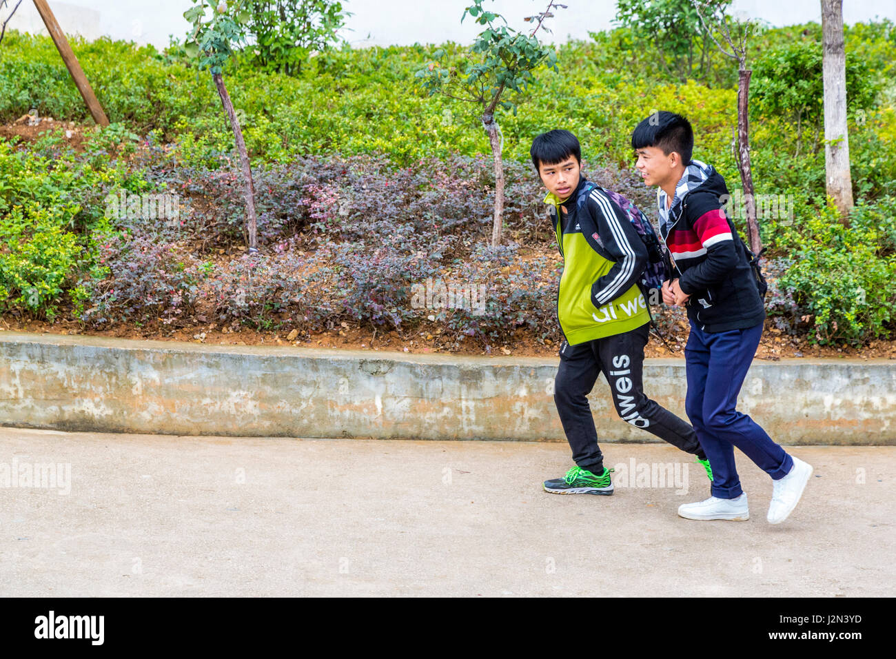 Kaili, Guizhou, Cina. Due ragazzi adolescenti camminando sul marciapiede. Foto Stock