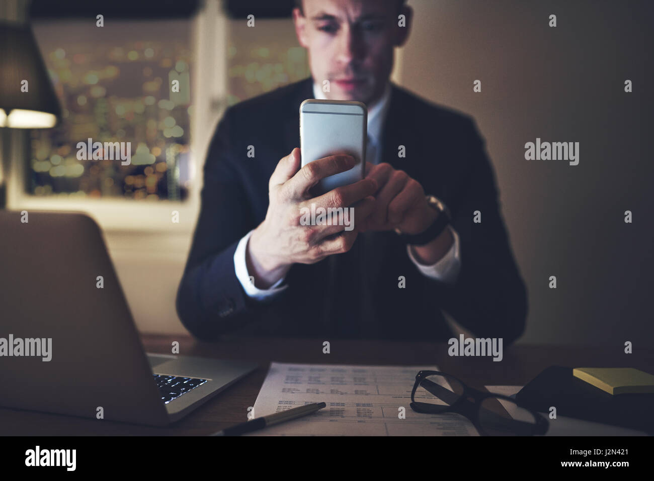 Un attenta gestione intelligente seduto in ufficio e navigare il suo smartphone. Foto Stock