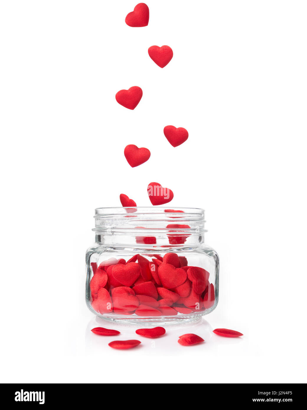 Cuori rossi piccoli che rientrano in un barattolo di vetro su sfondo bianco, concept per San Valentino o occasione speciale Foto Stock