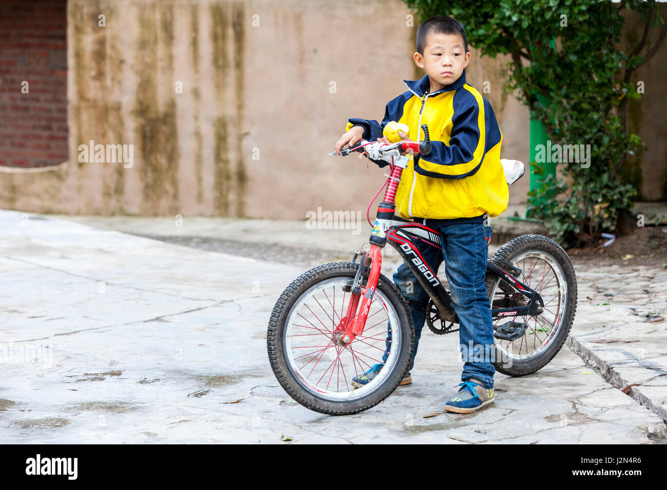 Matang, un villaggio Gejia nel Guizhou, Cina. Ragazzo giovane e la sua bicicletta, tenendo un Apple. Foto Stock