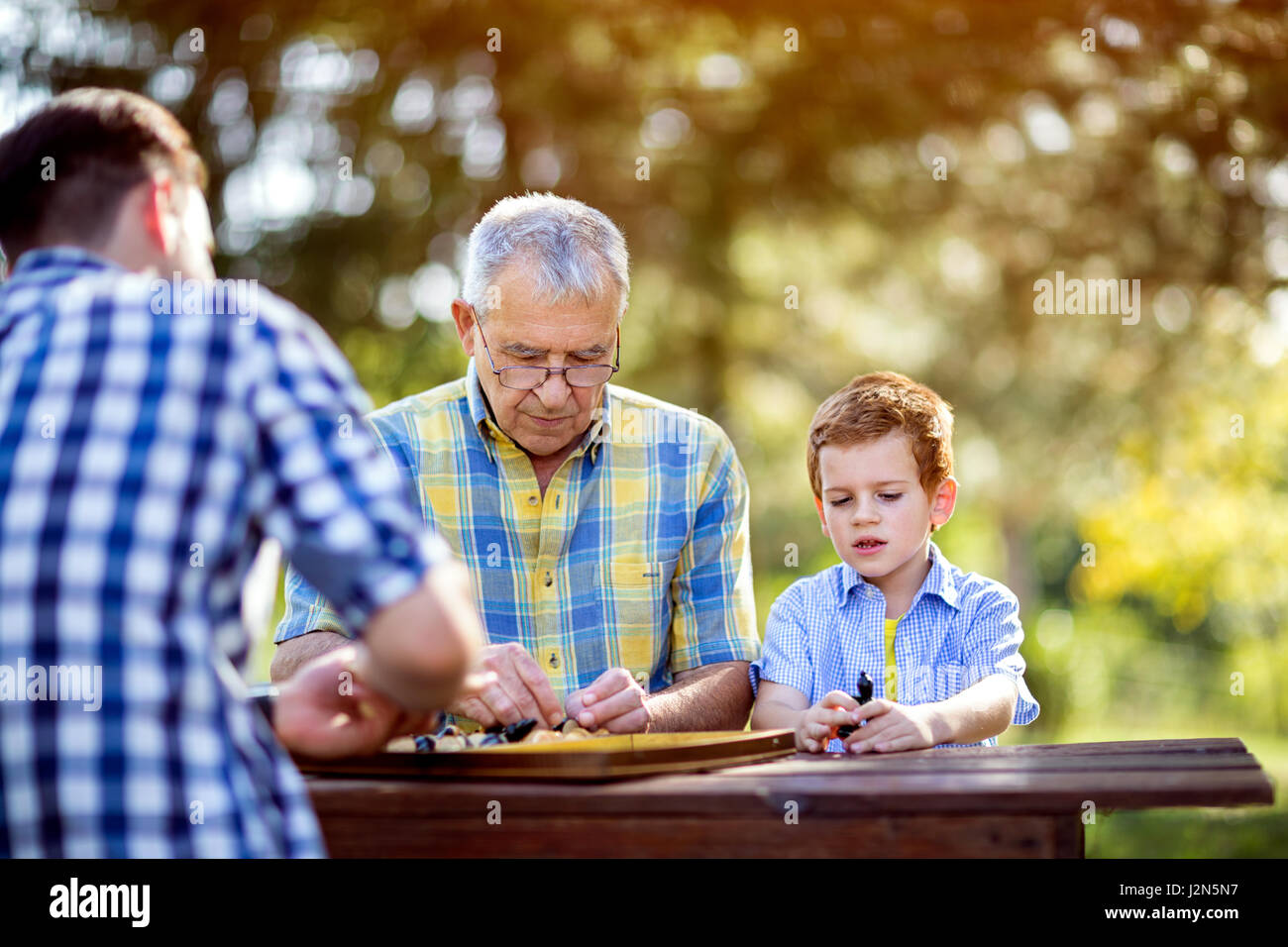 Little Boy e suo nonno giocare a scacchi nel parco Foto Stock
