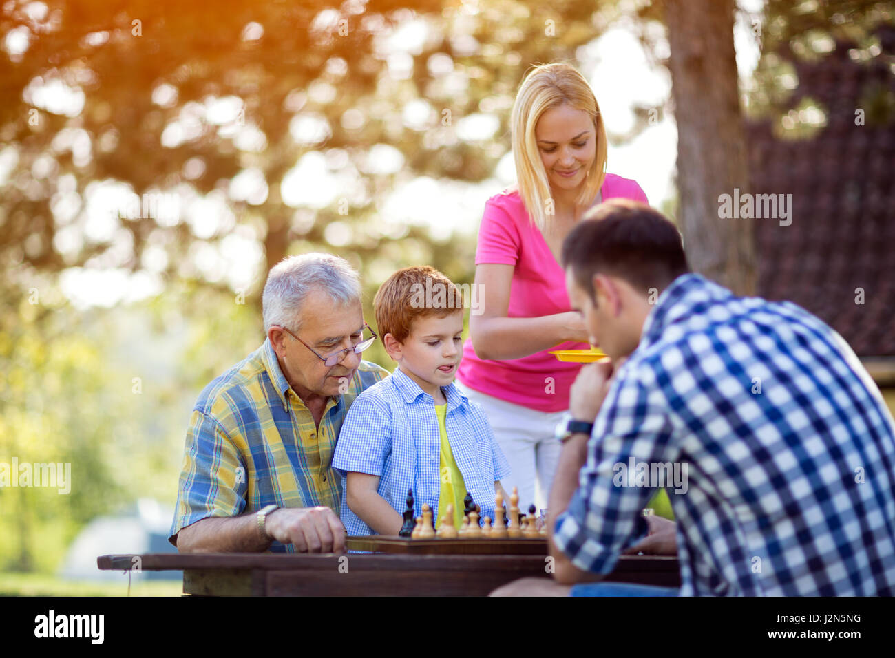 Famiglia seduti insieme in natura e giocare a scacchi Foto Stock