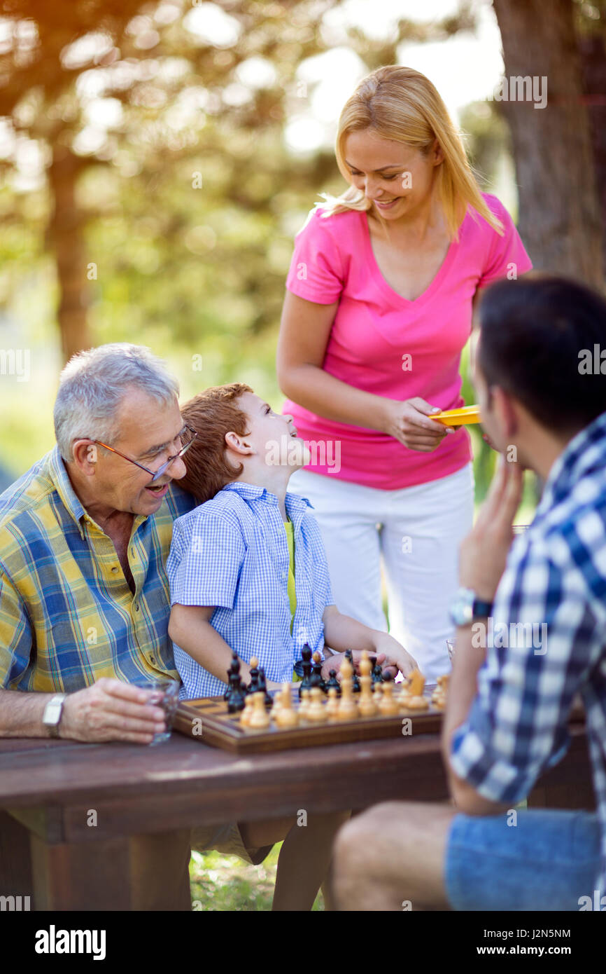 Ragazzo giocando a scacchi nel parco con la famiglia Foto Stock
