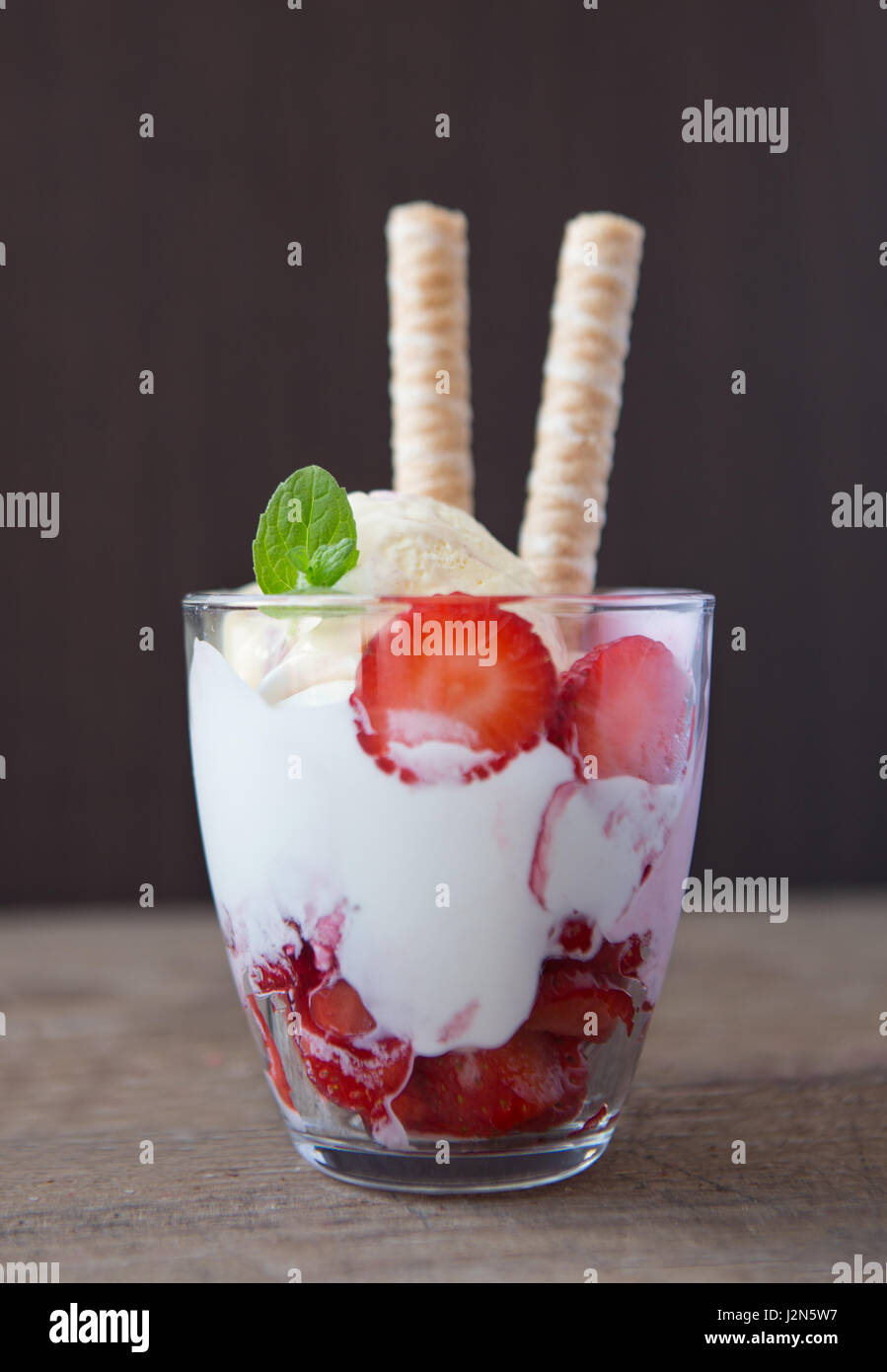Dessert in vetro con biscuit, fragola, gelato e panna Foto Stock