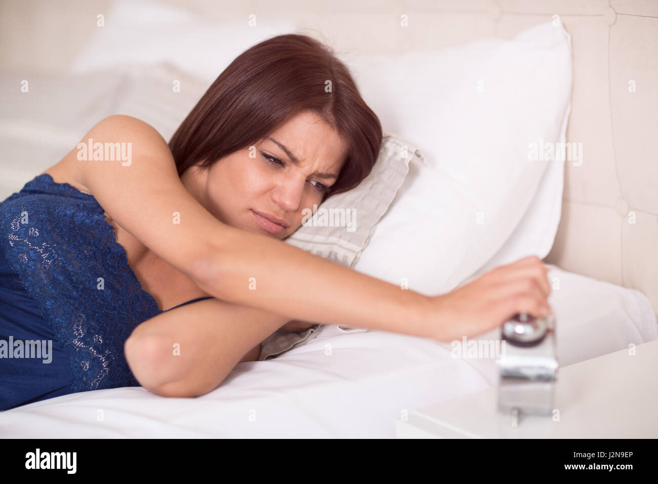 Giovane femmina la mattina sullenly guardare l'orologio Foto Stock