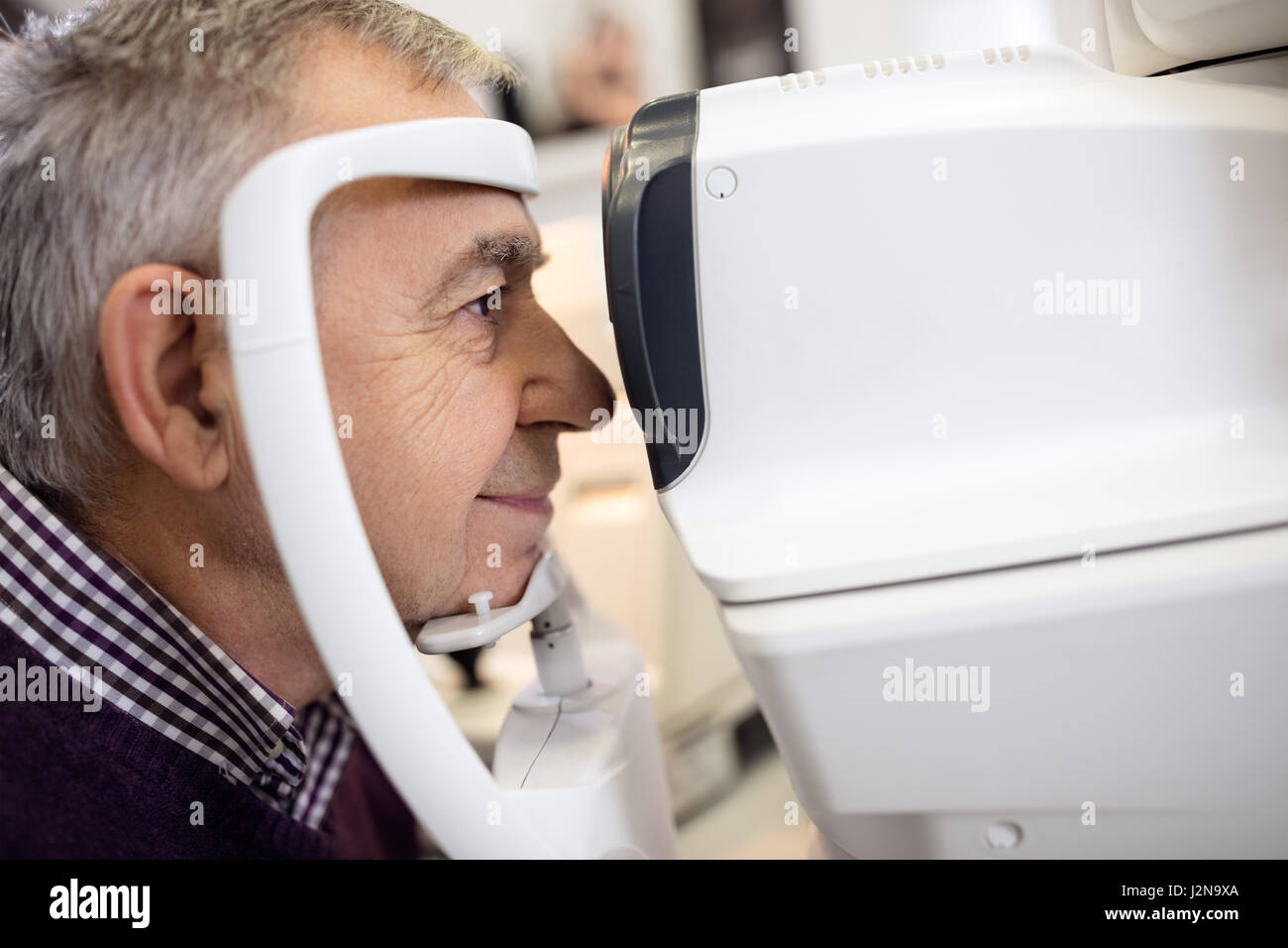 Close up di senior controllare i suoi occhi utilizzando apparecchiatura presso la clinica oculistica Foto Stock