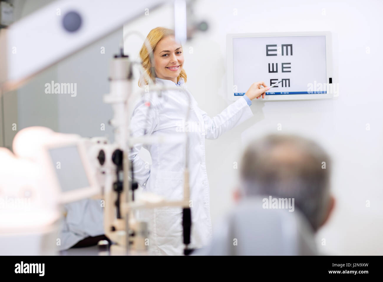 Bella donna bionda occhio medico mostra lettere nella sala di consultazione Foto Stock
