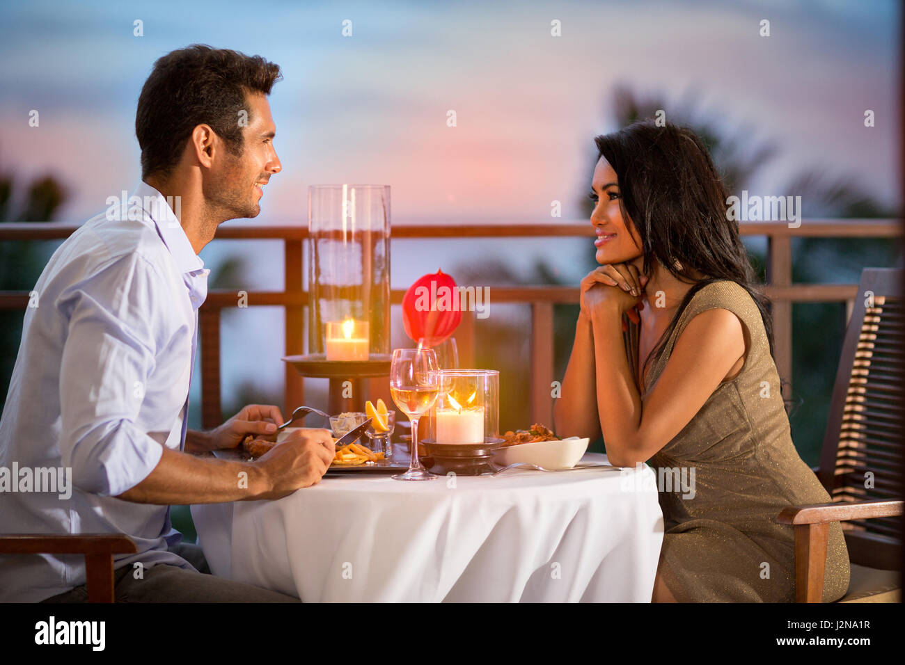 La condivisione di coppia romantica cena al tramonto sul resort tropicale Foto Stock