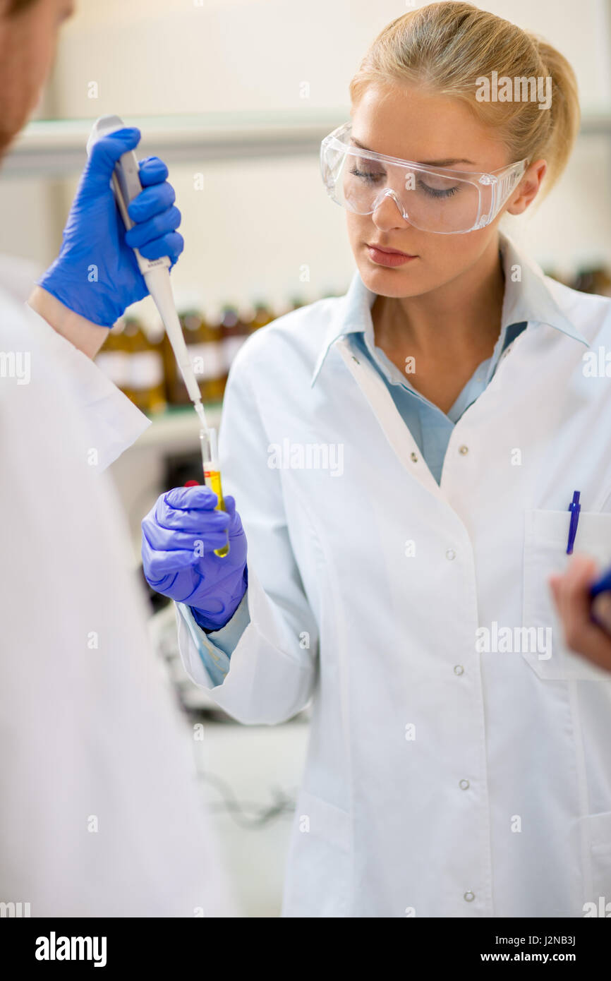 Assistente di laboratorio prendere il campione di liquido con moderne apparecchiature Foto Stock
