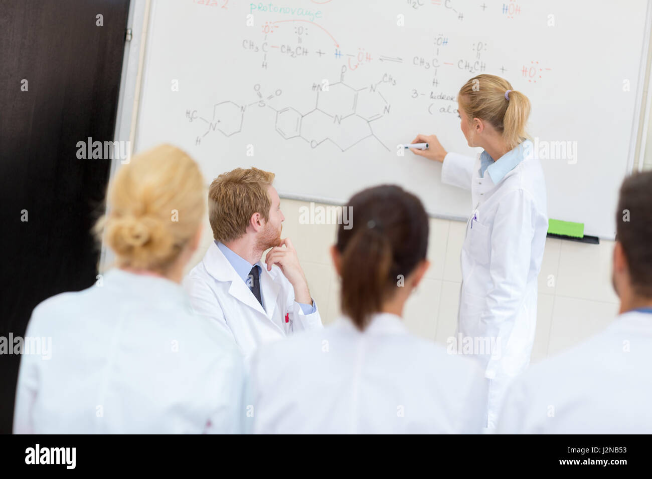 In classe studentessa scrivere formula chimica sulla lavagna Foto Stock