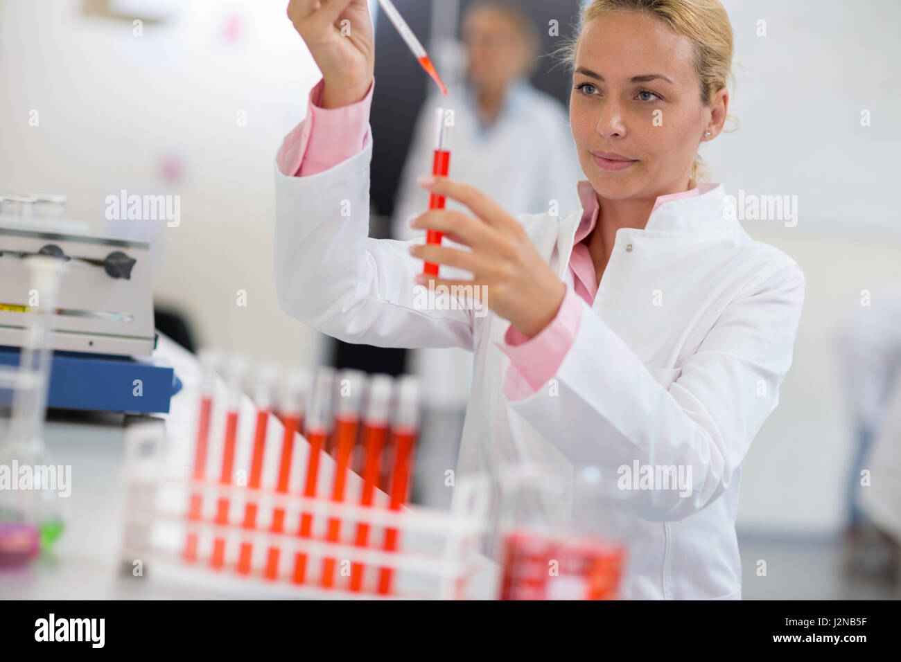 Giovane chimico liquido di campionamento con pipetta in laboratorio Foto Stock