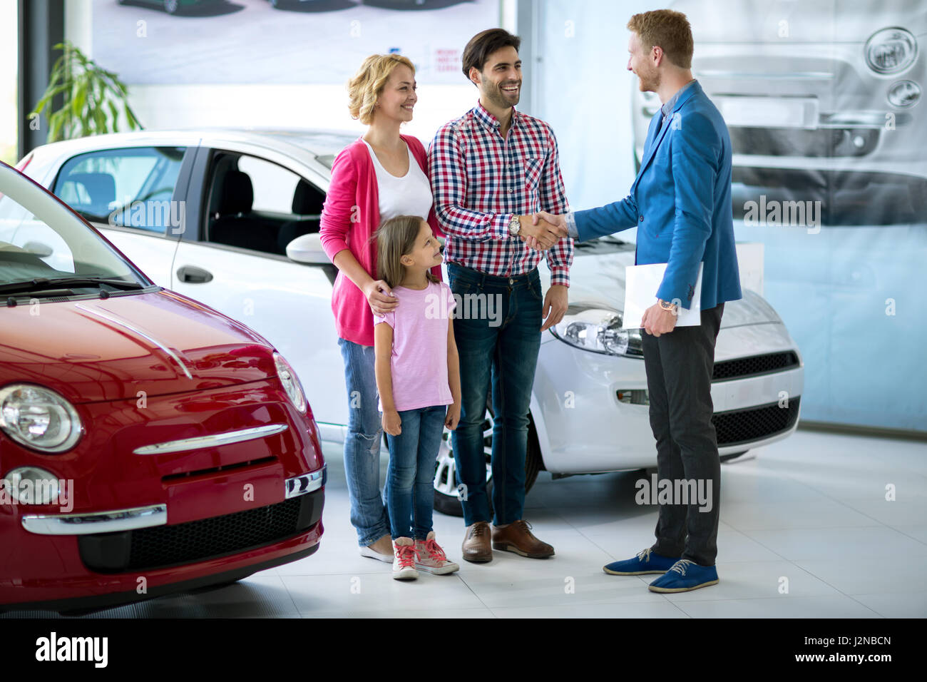 La famiglia felice acquistare nuove auto, auto handshaking del concessionario con il papà si è congratulato con la famiglia in una nuova auto Foto Stock