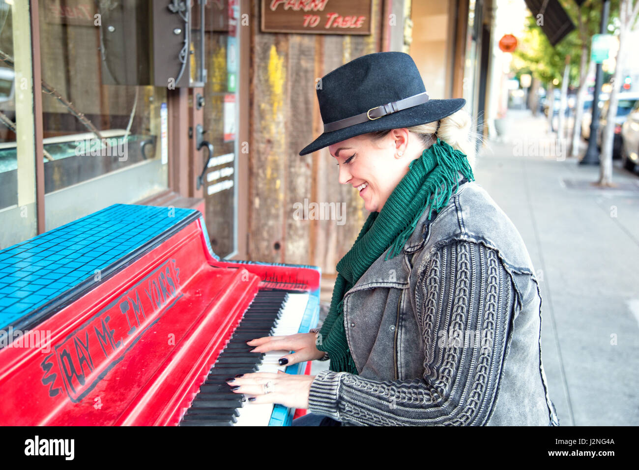 Una zona alla moda di 30 qualcosa di donna suona il pianoforte su una strada della citta'. Foto Stock