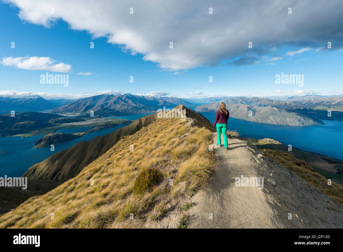 Donna escursionismo sul crinale, vista sulle montagne e sul lago, Roys picco, il lago Wanaka, Alpi del Sud, regione di Otago e Southland, Nuova Zelanda Foto Stock