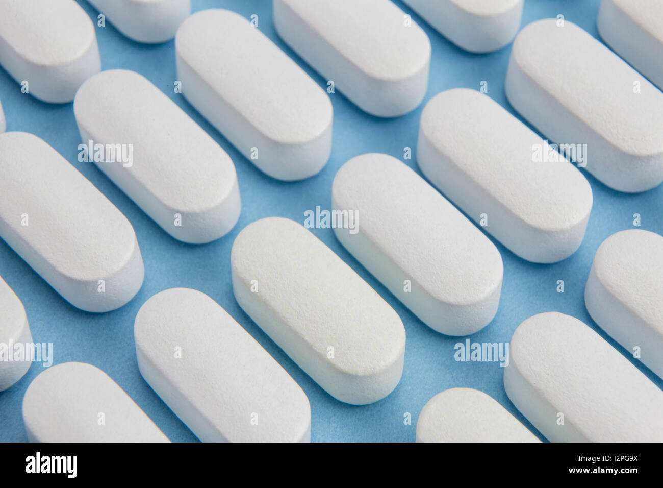 Alcune pillole allineati isolato su sfondo blu Foto Stock