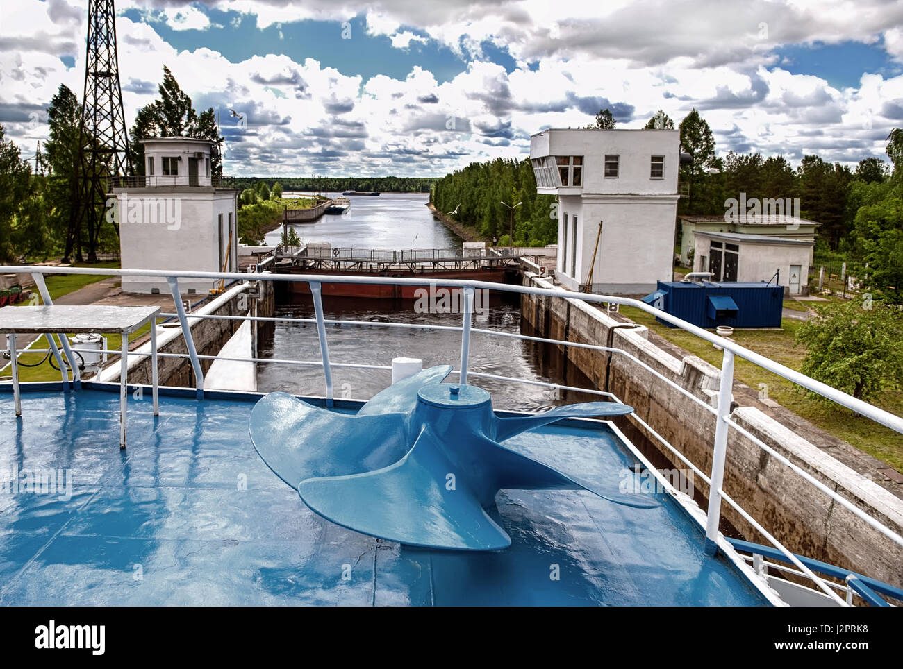 Un gateway di spedizione con le comunicazioni e gli edifici dal fiume nella giornata di sole con le nuvole nel cielo la vista dalla nave con la vite blu.. Foto Stock