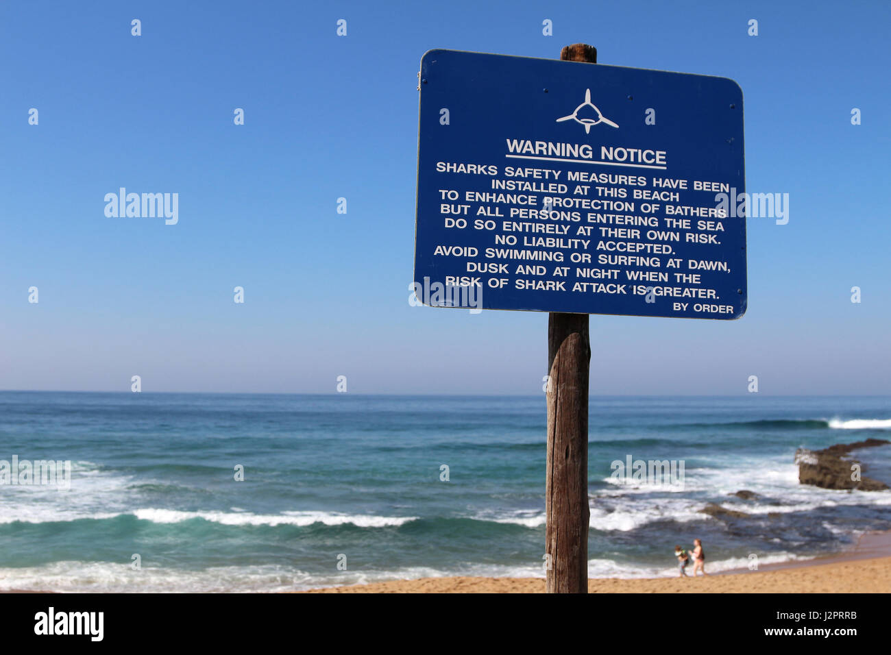Un segno blu mette in guardia contro il possibile rischio di squali in una spiaggia. Foto Stock
