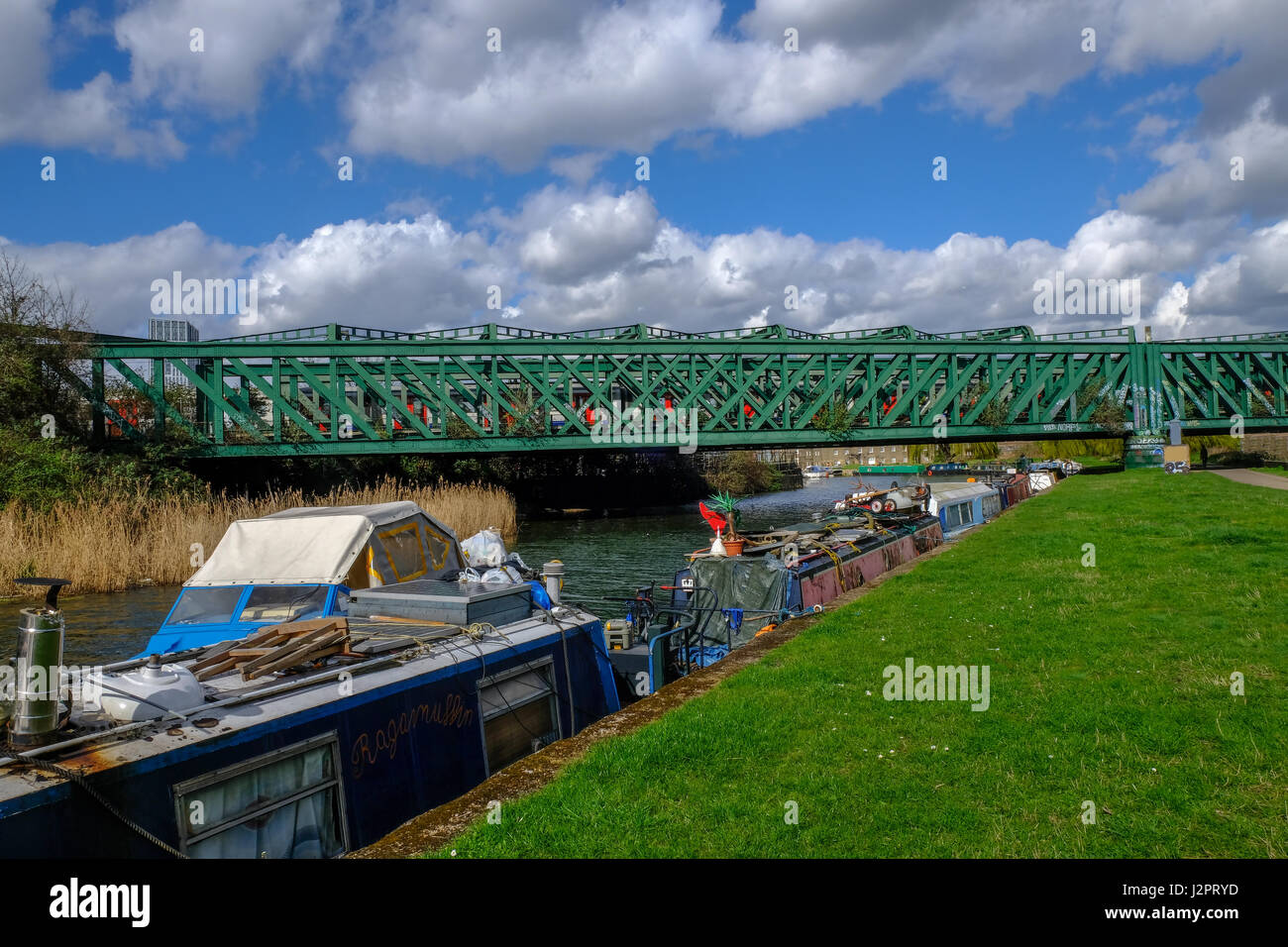 Fiume Lea vicino a prua con longboats e ponte ferroviario in primavera. Foto Stock