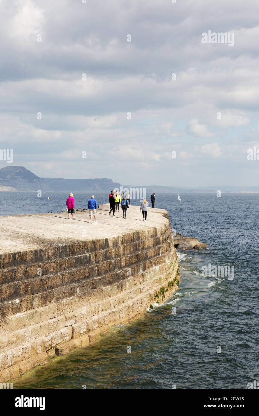 Lyme Regis Cobb Dorset - la gente che camminava sul Cobb, o parete di porto, Lyme Regis Harbour, Lyme Regis Dorset Regno Unito Foto Stock