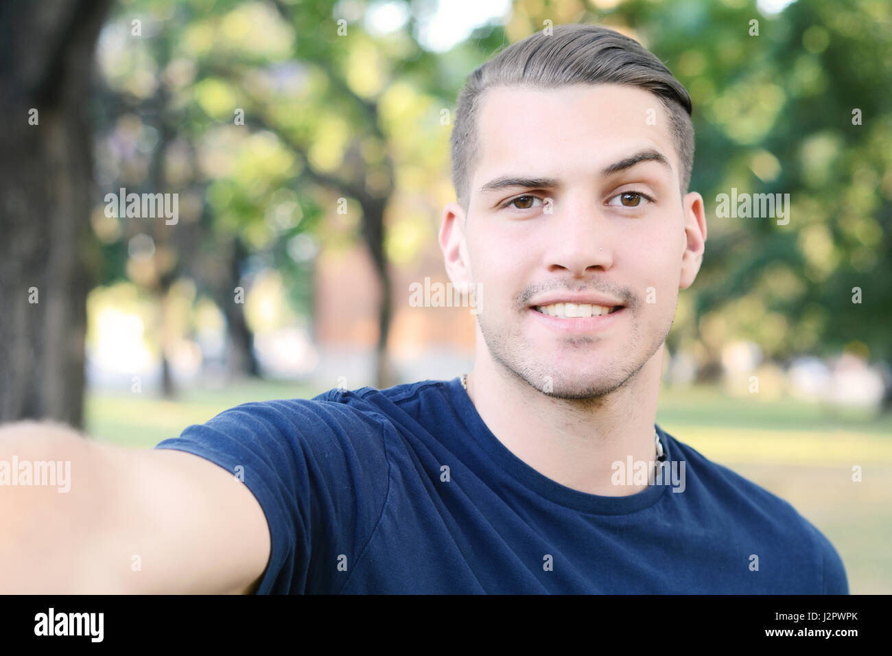 Giovane uomo latino tenendo un selfie in un parco. All'esterno. Foto Stock